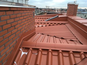 Na dachu o nachyleniu poniżej 5 stopni w oddali widać zbudowane z płyt OSB i docieplone wyjście na dach. Wyłaz na dachu płaskim