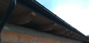 Detal wykonania szczytu budynku. Widać więźbę wykonaną na obrabiarce CNC i metalowe rynny. Ozdobna więźba z drewna klejonego warstwowo.