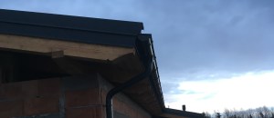 Detal wykonania szczytu budynku. Widać więźbę wykonaną na obrabiarce CNC i metalowe rynny. Ozdobna więźba z drewna klejonego warstwowo.