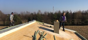 Warstwy docieplenia dachu widoczne z lewej. Na więźbie jest zamontowana nadbitka, płyta PIR, membrana, łaty i blachodachówka